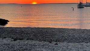 A sunset over a rocky beach with sailboats. - Gorgeous South Beach Contemporary 5 min walk to beach with AC, and WiFi (Edgartown)