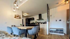 Una cocina moderna con comedor, suelo de madera y un otoman tapizado en piel.