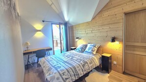 Un dormitorio con cama, lámparas de noche, un escritorio y una ventana.