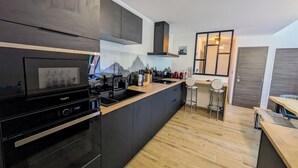 Una cocina moderna con electrodomésticos negros, una encimera de madera y una ventana con vistas a un paisaje montañoso.