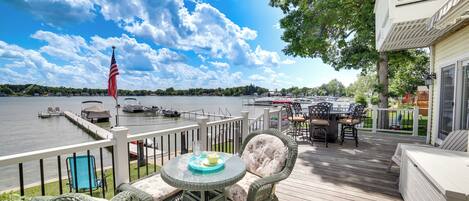 A deck with wicker furniture, a table with a glass, and an American flag.