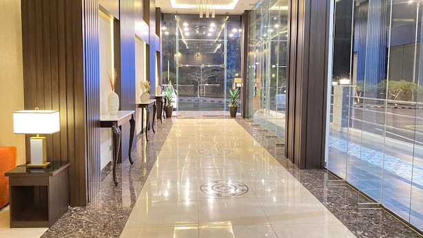Un moderno vestíbulo de hotel con piso de mármol pulido, una recepción y un muro de vidrio con vistas a la calle.