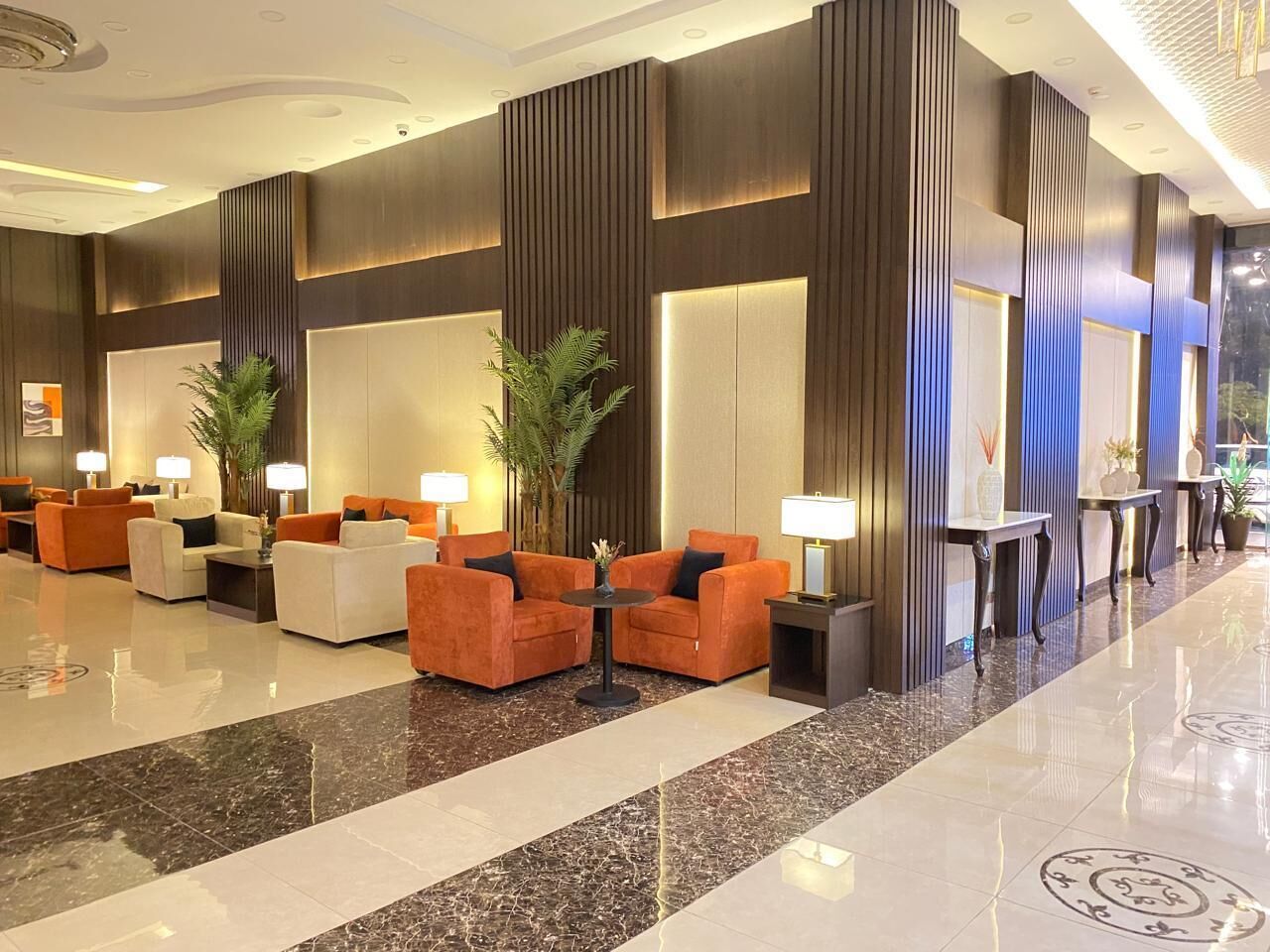 Un vestíbulo moderno con zonas de estar, un mostrador de recepción y una planta decorativa.