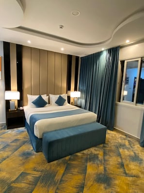 A modern hotel room with a large bed, two bedside tables with lamps, a wooden floor, and a window with curtains. - فندق فصل الصيف امان المنسك (Abha)