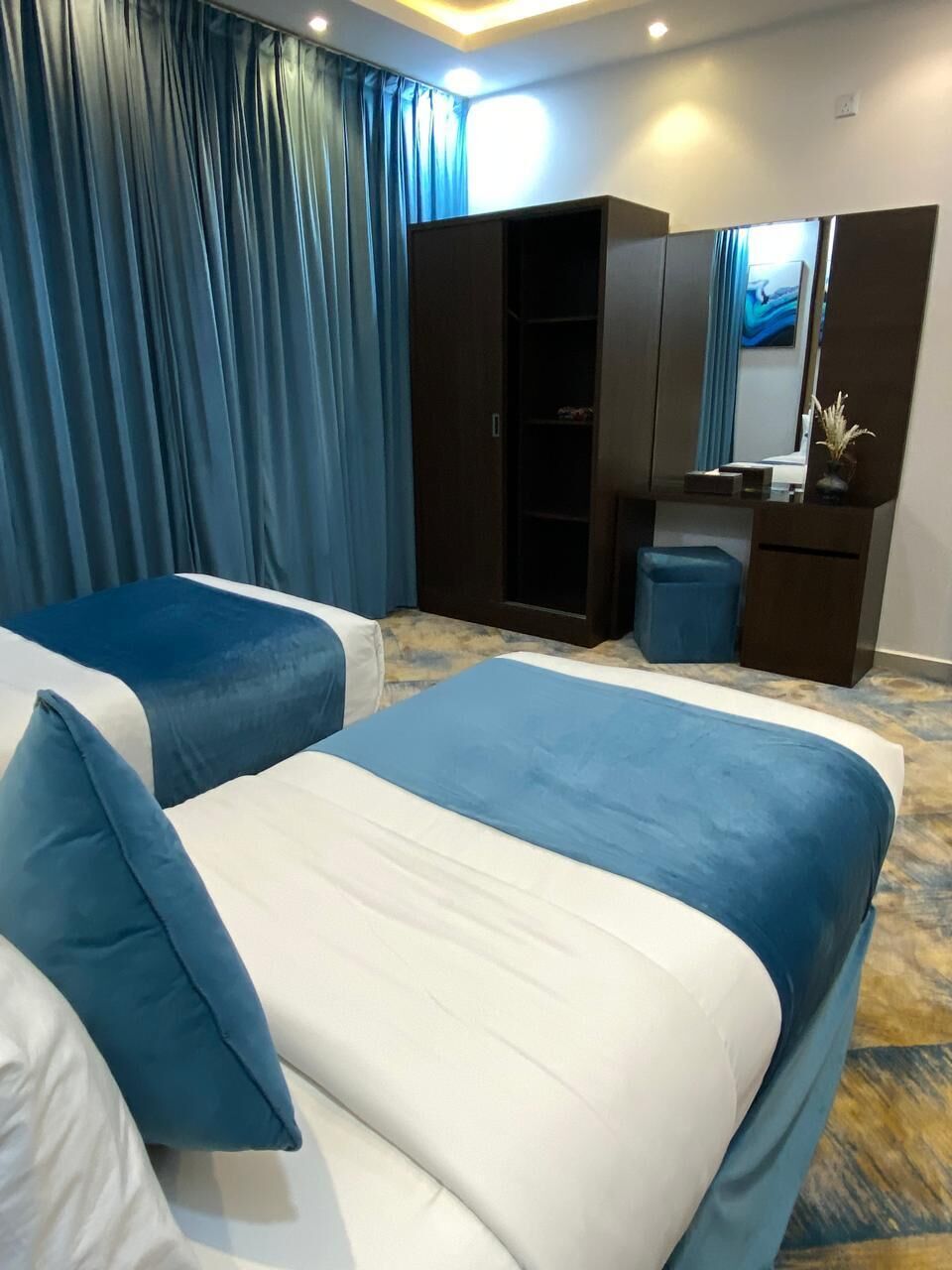 Habitación de hotel con dos camas, un armario, un espejo y un escritorio.