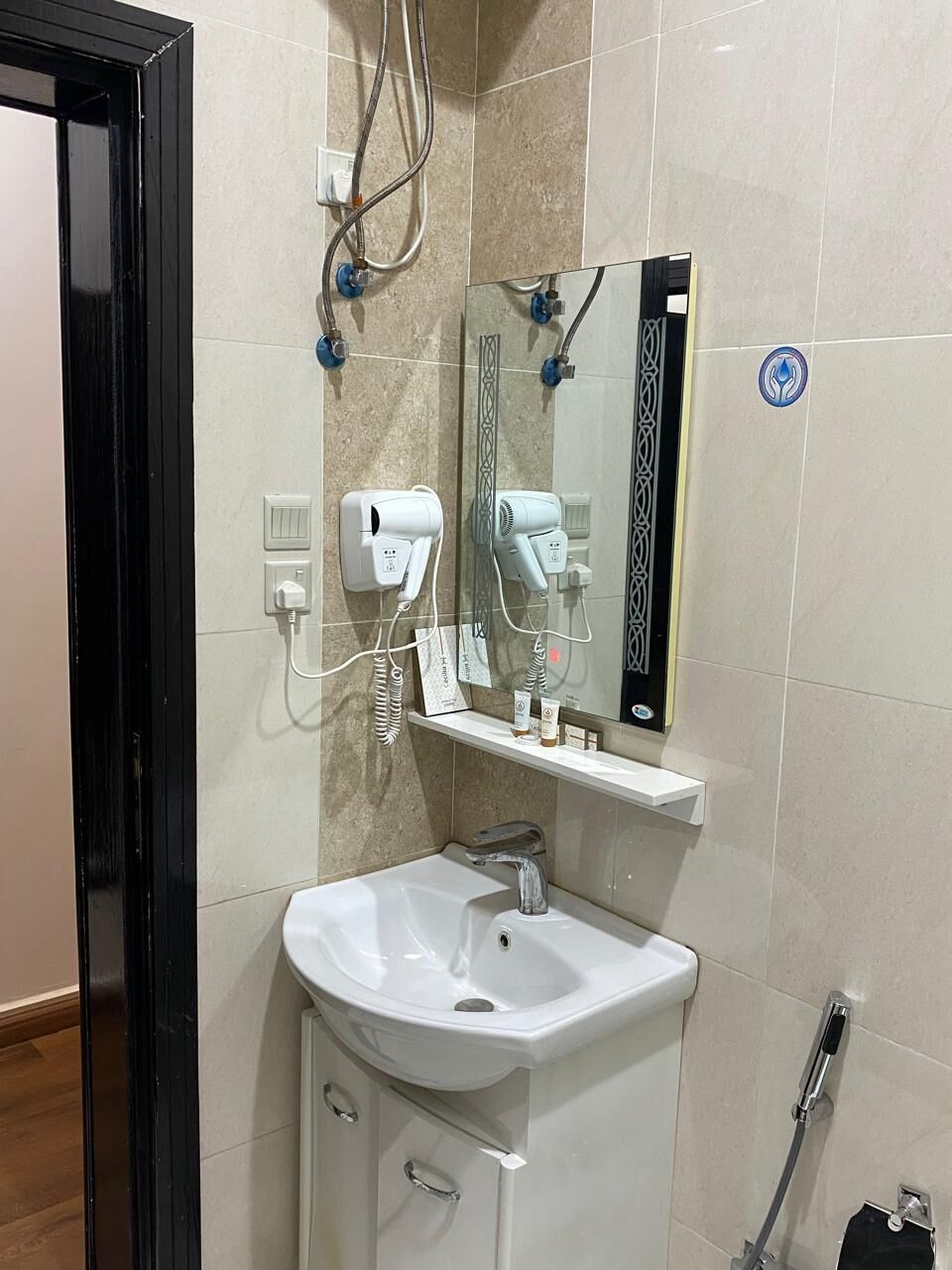 A bathroom with a white sink, a mirror, a hairdryer, and a towel rack.