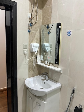 A bathroom with a white sink, a mirror, a hairdryer, and a towel rack. - فندق فصل الصيف امان المنسك (Abha)