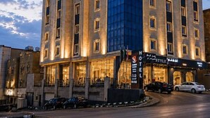 Un hotel de varios pisos con un llamativo letrero que dice 'Summer Season', un restaurante 'Hotel Style' y un amplio frente de vidrio.