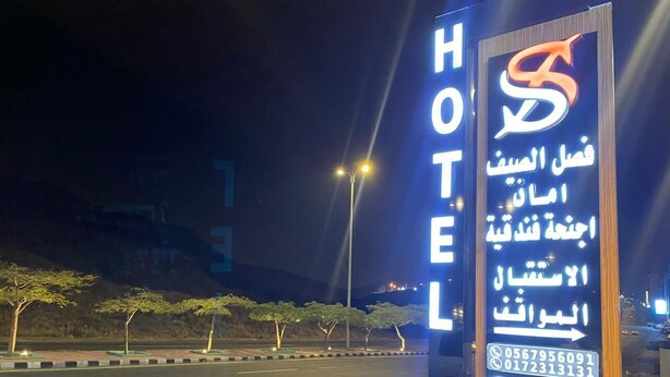 Un cartel de hotel con texto en árabe y un logotipo, que indica el nombre del hotel y sus servicios.