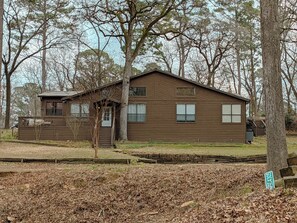 A two-story wooden cabin with a porch, surrounded by trees. - Sprawling 3-bedroom house in delightful Scroggins with WiFi, AC and lakeview (Scroggins)