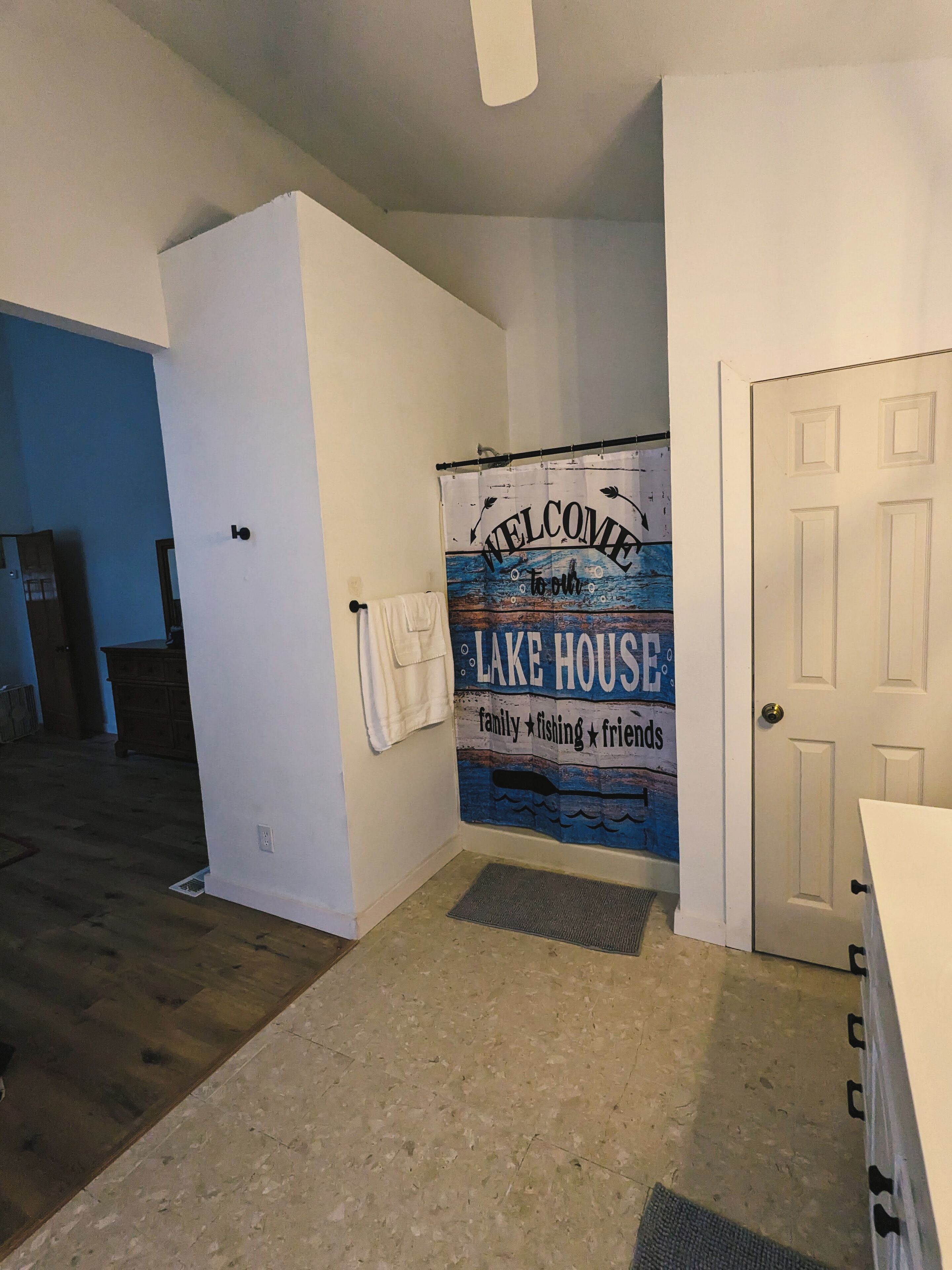 Un pasillo con un cartel de bienvenida para Lake House, una puerta blanca y un suelo de madera.