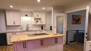 Una cocina moderna con armarios blancos, encimera de madera y un lavamanos empotrado.