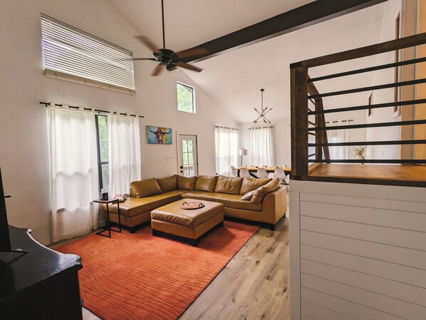 A modern living room with a sectional sofa, a coffee table, and a ceiling fan.