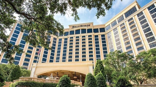 A large, multi-story hotel with a prominent entrance and a well-maintained garden in front.