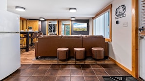 A modern kitchen with a dining area, a large window with a scenic view, and a logo on the wall. - Buck's Den - Snowmobile Trails, Trailer Parking, Near hiking, golfing, Sugarloaf (Eustis)