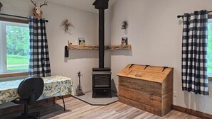 A cozy room with a fireplace, a table with a floral tablecloth, and a chair. - New 4-bedroom for rent during EAA!  Sleeps 17, large loft and three bedrooms!  (Wautoma)