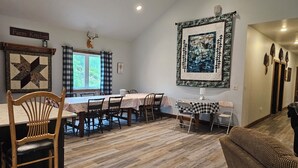 A dining area with a large table, chairs, and a wall-mounted artwork. - New 4-bedroom for rent during EAA!  Sleeps 17, large loft and three bedrooms!  (Wautoma)