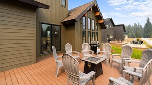 A modern house with a deck featuring outdoor furniture and a grill.