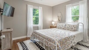 Ein Schlafzimmer mit einem Bett, einem Nachttisch, einer Lampe und einem Traumfänger an der Wand.