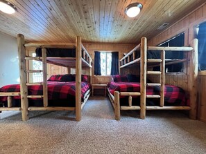 Une cabine avec des lits superposés, des murs en bois et un sol recouvert de moquette.
