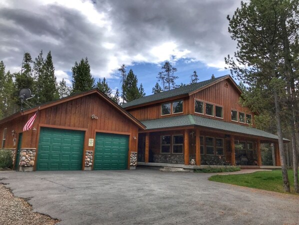 Un bâtiment en bois à deux étages, doté d’un porche couvert et d’un garage vert.
