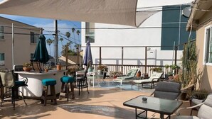 Un patio al aire libre con bar, mesas y sillas, y una piscina.