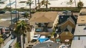 Zona residencial costera con vista a la playa, palmeras y una combinación de arquitectura moderna y tradicional.