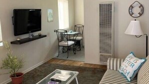 Una sala de estar con televisor, mesa de centro, sofá a rayas, lámpara y decoración mural.
