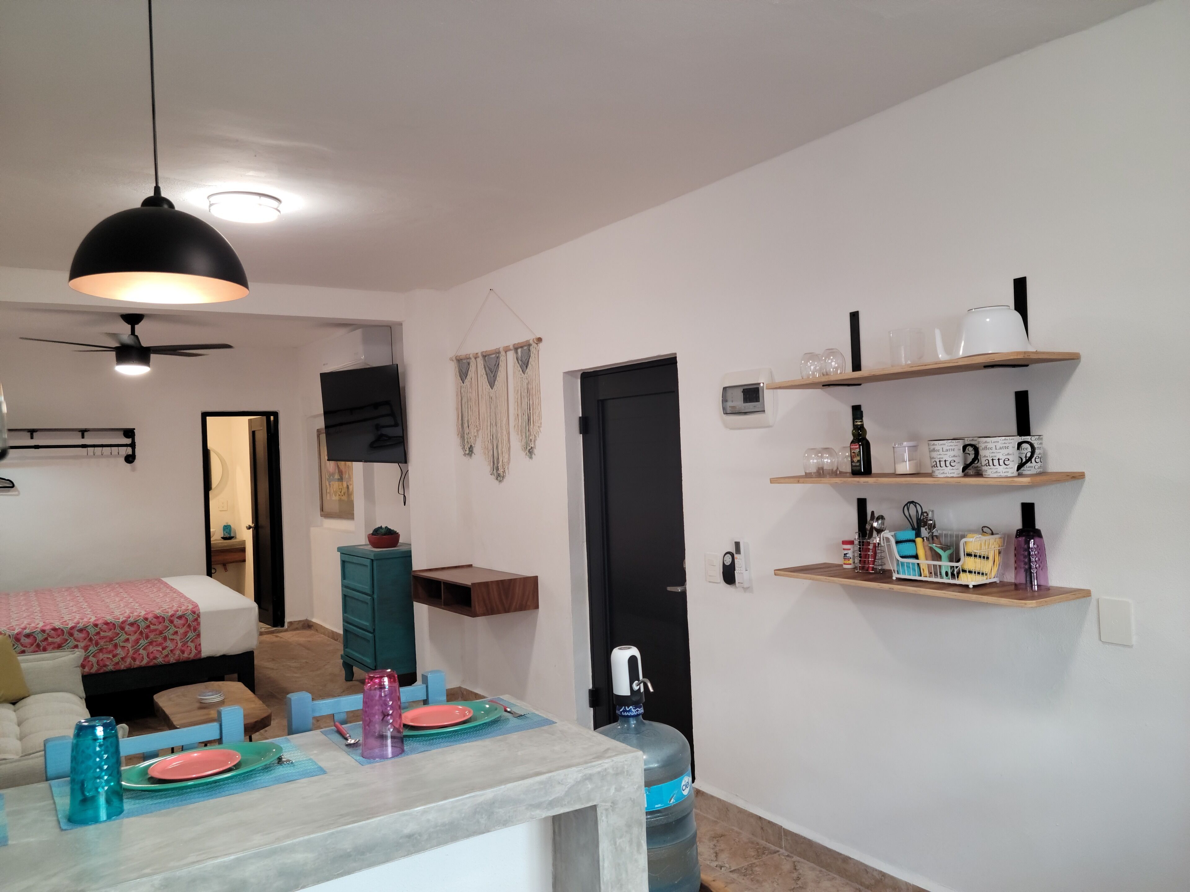 Un salon moderne comprenant un coin repas, un téléviseur fixé au mur et un ventilateur de plafond.