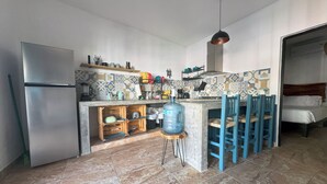 Een kleine keuken met een koelkast, een waterdispenser en een betegelde achterwand.