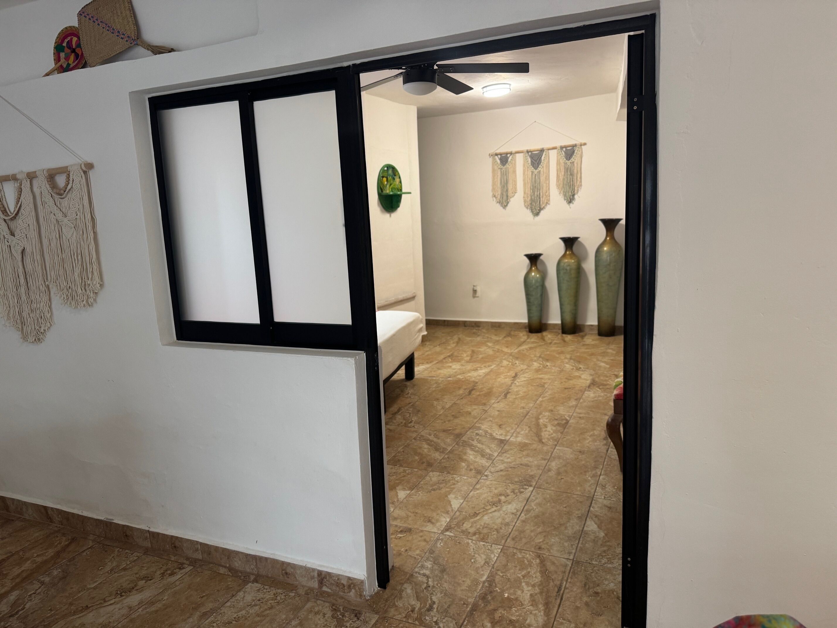 Une chambre avec un lit, un ventilateur de plafond et des éléments décoratifs accrochés aux murs.