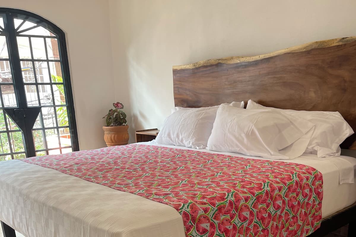 A bed with a patterned bedspread, white pillows, and a wooden headboard.