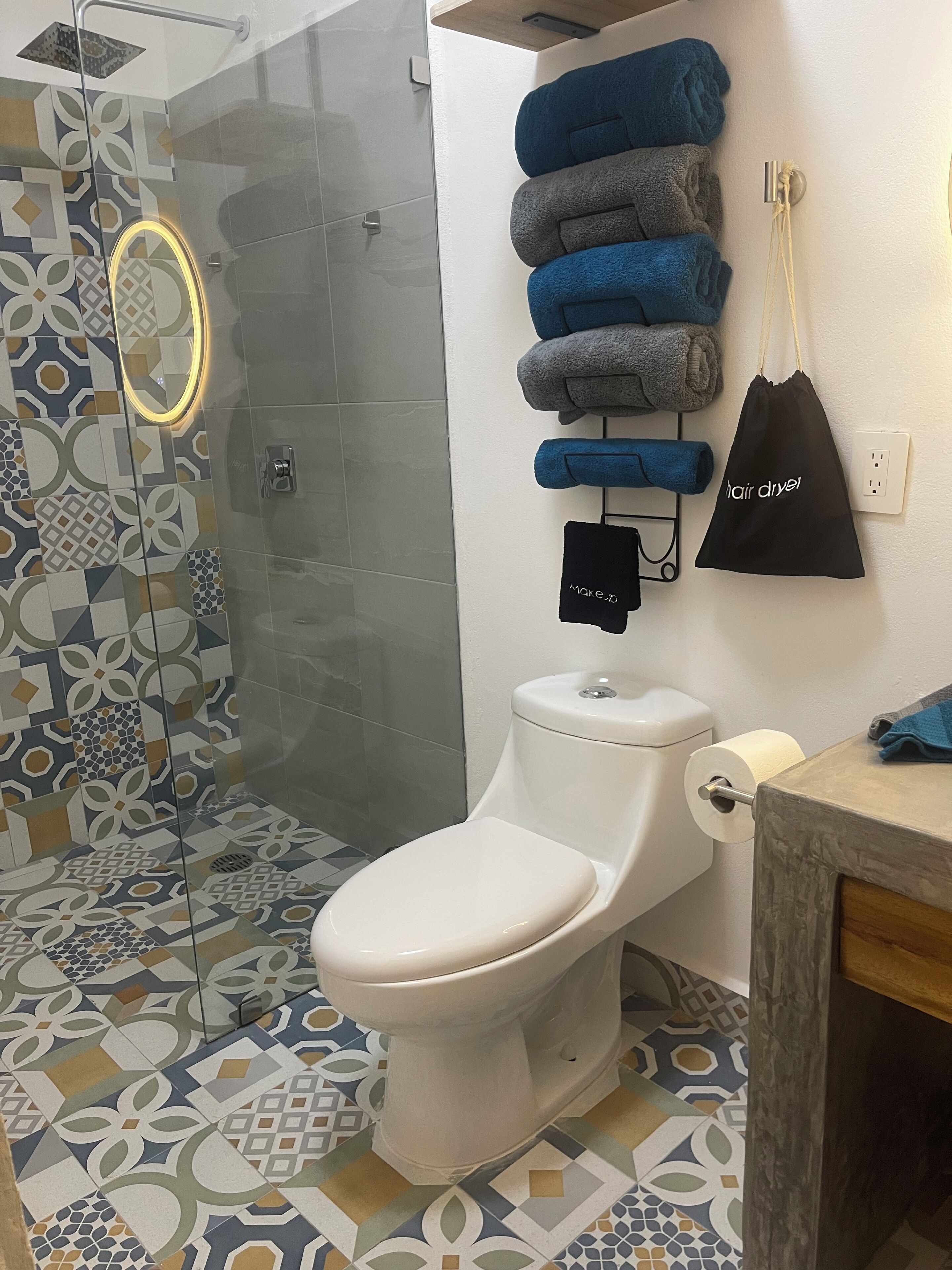 A bathroom with a toilet, a glass shower enclosure, and patterned tiles.