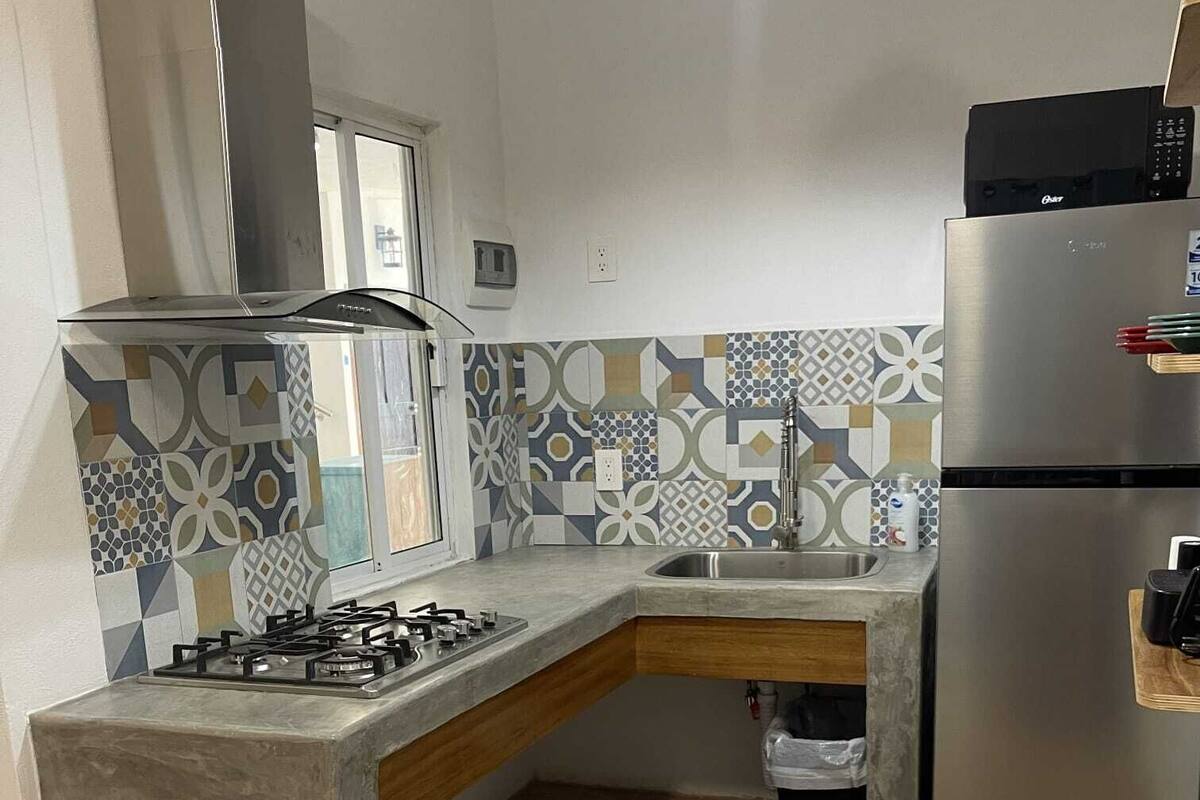A kitchen with a gas stove, stainless steel refrigerator, and patterned backsplash.