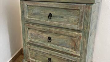 A rustic wooden chest of drawers with three drawers and a red bowl on top.