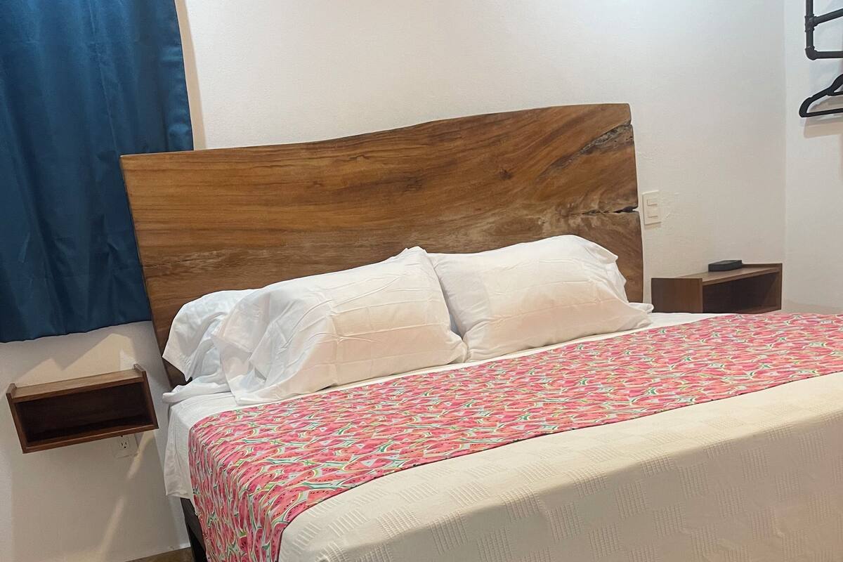 A bed with a wooden headboard, a white mattress, and a patterned bedspread.