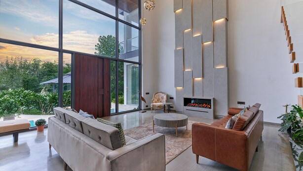Una sala de estar moderna con un ventanal grande, una chimenea y una escalera.