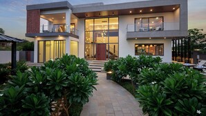 Una casa moderna de dos pisos con una entrada amplia, ventanas grandes y un jardín bien cuidado.