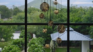 Vista a través de una ventana con luces esféricas colgantes, un jardín y una casa con techo de metal.