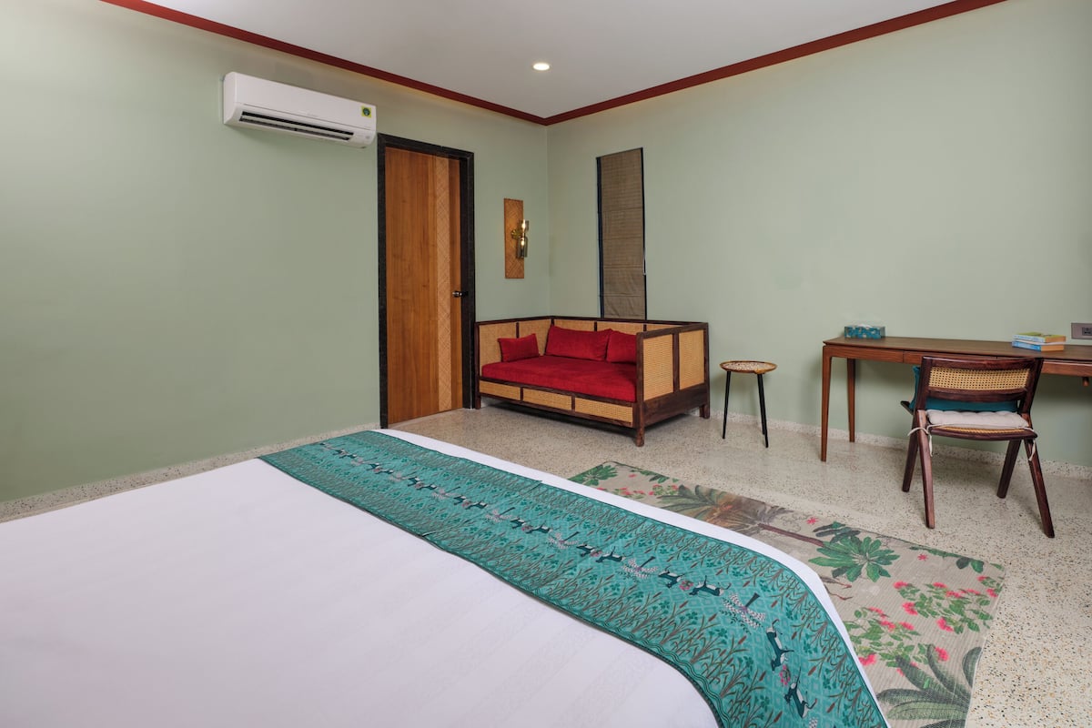 Un dormitorio con cama, sofá, mesita y una silla.