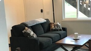 A dark-colored sofa with two pillows, a wooden coffee table, and a chair. - Ground Floor End Unit in Midtown Anchorage (Anchorage)