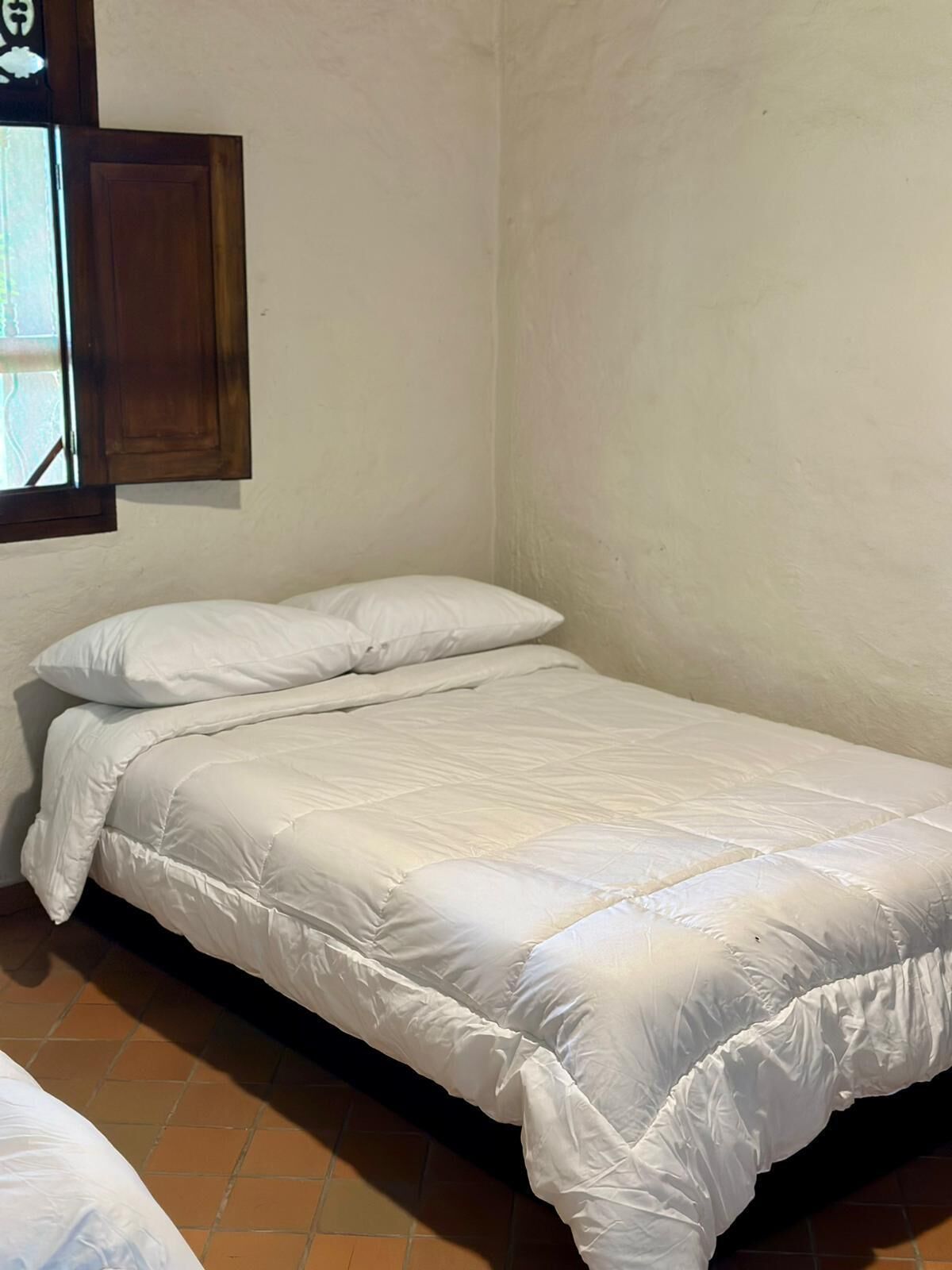 A small, single-bed room with a wooden door and a window.