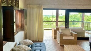 A room with a blue sofa, wicker furniture, and a balcony with a view of greenery. - Villa Privada eje Cafetero (Quindío)
