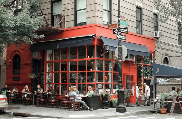 A red brick building with a black awning, outdoor seating, and a street sign indicating 'Bedford St.'