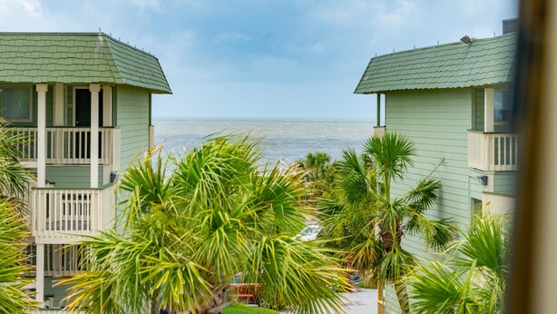 A view of two green buildings with balconies overlooking a beach. - Top Floor condo, Pool, across from Beach & Pier Access! - 310C Oceanside (Isle Of Palms)
