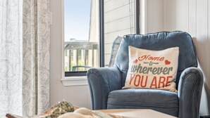 A blue armchair with a cushion that reads "Home is wherever you are." - Top Floor condo, Pool, across from Beach & Pier Access! - 310C Oceanside (Isle Of Palms)