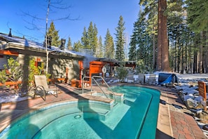 A pool area with a clear blue pool, a wooden deck, and a lounge chair.