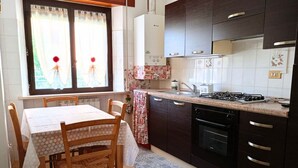 A kitchen with a dining table, chairs, a stove, oven, and cabinets. - SE115 - Marotta, comfortable two-room apartment with parking (Marotta)