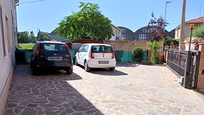 A paved driveway with two cars parked, a stone wall, and a residential building in the background. - SE115 - Marotta, comfortable two-room apartment with parking (Marotta)