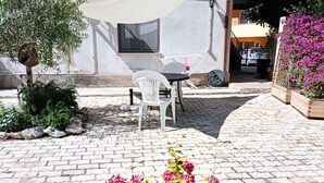 A patio with a table and chairs, a white chair, a small table, and a potted plant with pink flowers. - SE115 - Marotta, comfortable two-room apartment with parking (Marotta)